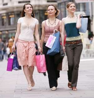 Three young girls are shopping for fashion jewelry at an outdoor mall
